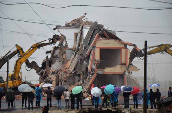 La gente observa la demolición de una casa en Wenling, provincia de Zhejiang, después de que su due?o llegara a un acuerdo con el gobierno local. [China Daily]