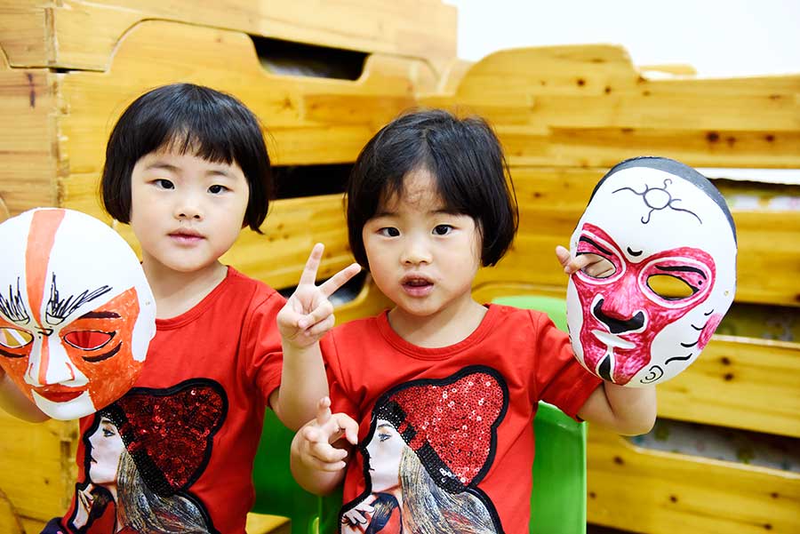 Dos ni?os muestran las máscaras faciales que hicieron de los personajes de la ópera de Pekín en la ciudad de Hefei, provincia de Anhui, el 3 de junio de 2016. [Foto de Ge Yinian/Asianewsphoto]