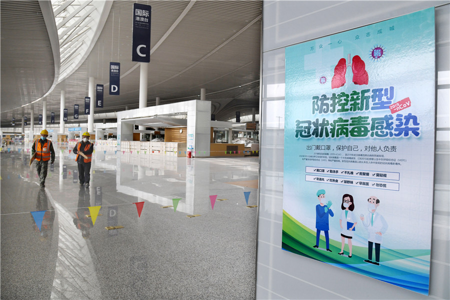 Dos hombres caminan frente a una sala terminal del Aeropuerto Internacional Jiaodong de Qingdao, provincia de Shandong, este de China, el 25 de marzo de 2020. [Foto / Xinhua]