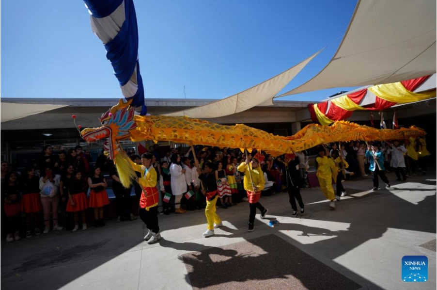 Imagen del 26 de septiembre de 2024 de estudiantes realizando una presentación de la danza del dragón durante el 20° aniversario de la denominación como República Popular China de una escuela primaria estatal en el barrio Casavalle, en Montevideo, capital de Uruguay. Con coloridas danzas y presentaciones musicales, cientos de ni?os uruguayos celebraron el 20° aniversario de la denominación como República Popular China de una escuela primaria estatal de Montevideo, que tiene el apoyo de la Embajada china. (Xinhua/Nicolás Celaya)